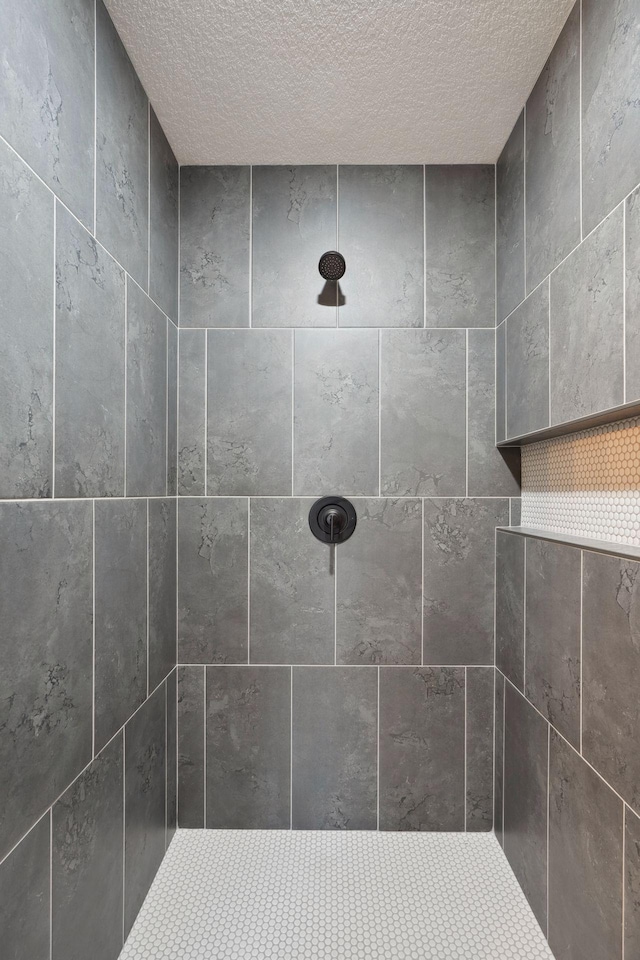 full bath with a textured ceiling and tiled shower
