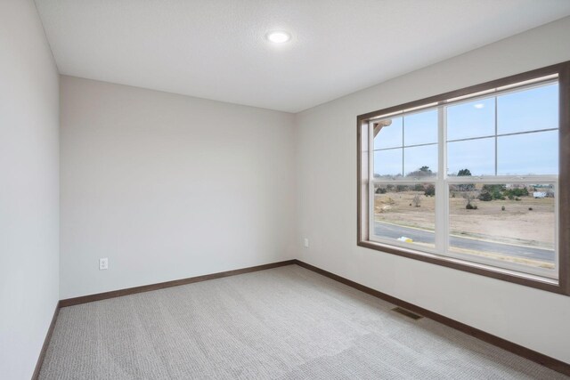 carpeted empty room featuring recessed lighting, visible vents, and baseboards