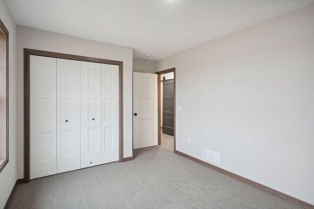 unfurnished bedroom featuring baseboards, visible vents, carpet floors, and a closet