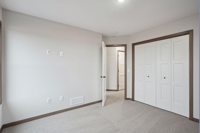 unfurnished bedroom with baseboards, visible vents, a closet, and carpet
