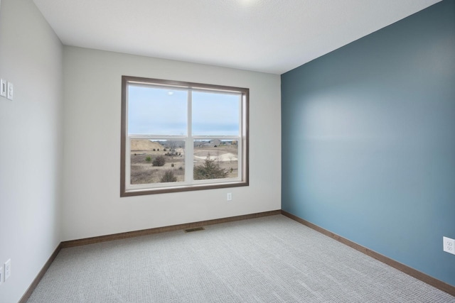 spare room with carpet flooring, baseboards, and visible vents