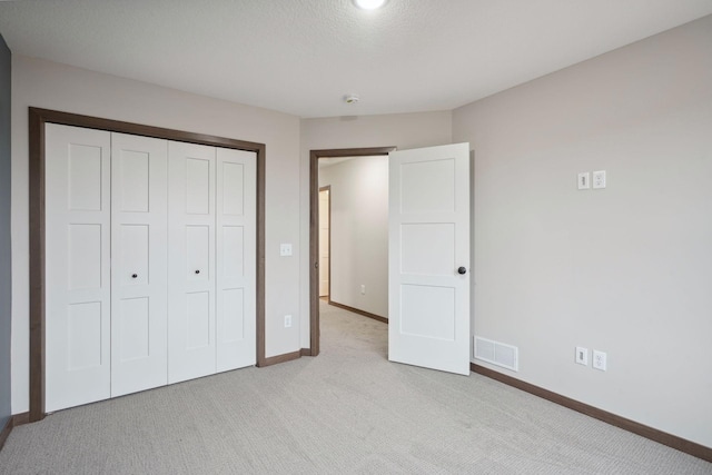 unfurnished bedroom featuring a closet, visible vents, light carpet, and baseboards