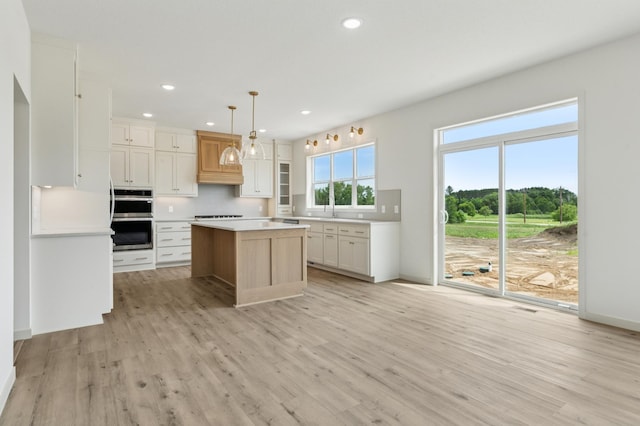 21959 Edison Ct NW, East Bethel, MN 55011 - kitchen featuring double oven, light wood-style flooring, recessed lighting, a center island, and light countertops