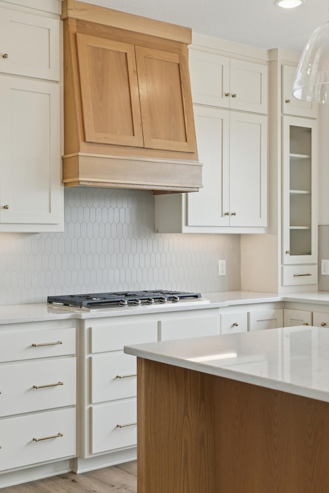 21959 Edison Ct NW, East Bethel, MN 55011 - kitchen with premium range hood, stainless steel gas stovetop, backsplash, and white cabinets