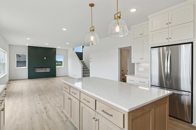 21959 Edison Ct NW, East Bethel, MN 55011 - kitchen featuring freestanding refrigerator, a large fireplace, light wood-style floors, a kitchen island, and light countertops