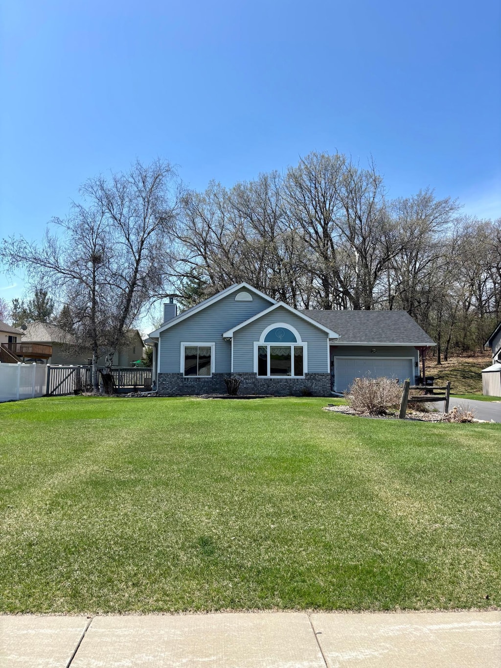 ranch-style house with a garage, fence, a chimney, and a front yard