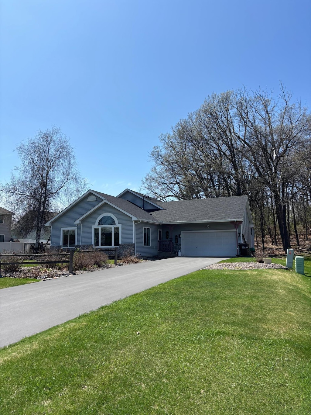 ranch-style house featuring an attached garage, a front lawn, and concrete driveway