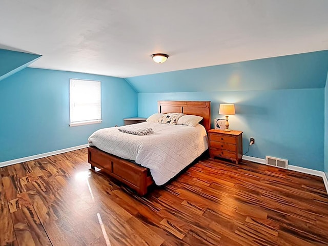 bedroom with baseboards, vaulted ceiling, wood finished floors, and visible vents