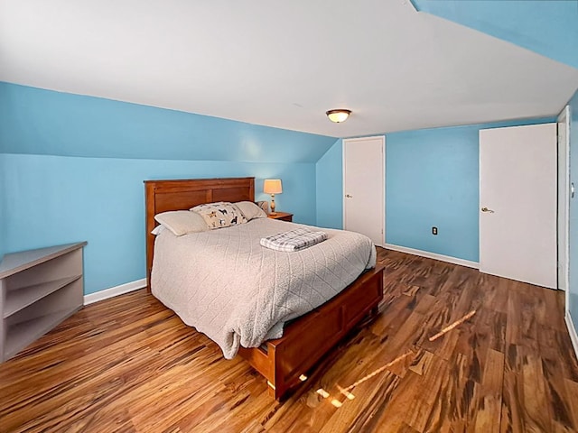 bedroom featuring baseboards, lofted ceiling, and wood finished floors