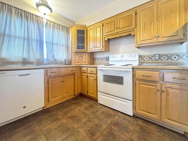 kitchen with white appliances, dark tile patterned flooring, a sink, and light countertops