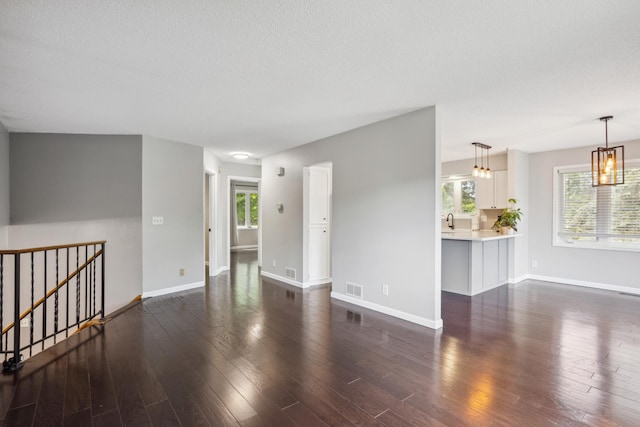 1112 Gabbert Cir, Eagan, MN 55123 - empty room featuring dark wood-style flooring, baseboards, a chandelier, a sink, and a textured ceiling