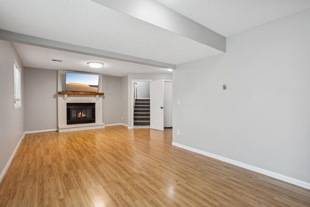 1112 Gabbert Cir, Eagan, MN 55123 - unfurnished living room with a brick fireplace, light wood-style flooring, stairs, baseboards, and a textured ceiling