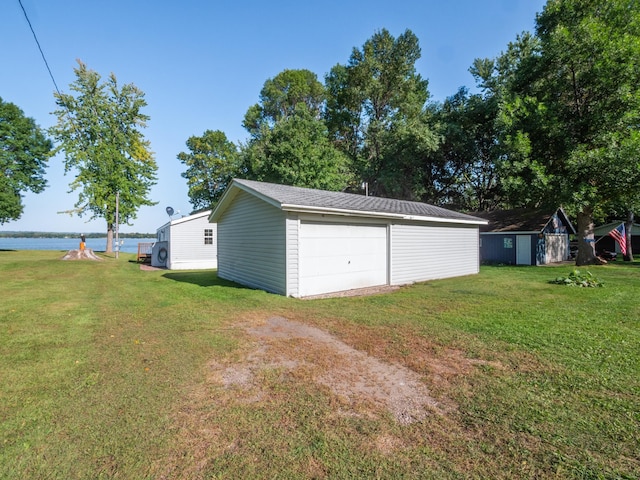 detached garage with a water view and driveway