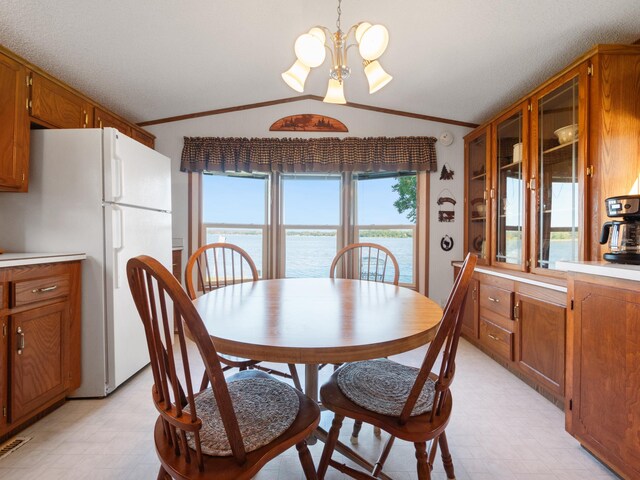 dining room featuring crown molding, light floors, vaulted ceiling, and a notable chandelier