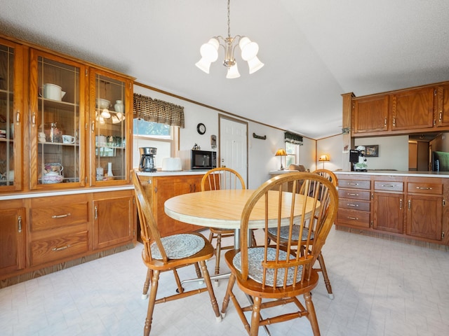 dining room featuring light floors, a chandelier, lofted ceiling, and ornamental molding