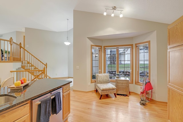kitchen featuring dark stone counters, dishwashing machine, lofted ceiling, and light wood-style floors