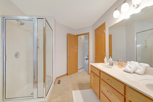 full bathroom with double vanity, a sink, a shower stall, and tile patterned floors
