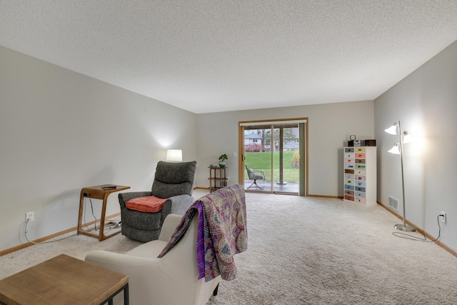 living area with a textured ceiling, visible vents, and carpet floors