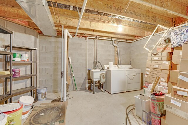 unfinished basement featuring separate washer and dryer, concrete block wall, and a sink