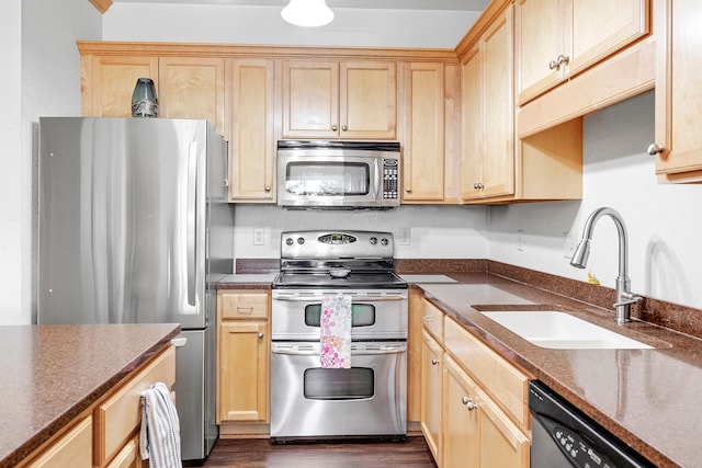 kitchen featuring appliances with stainless steel finishes, a sink, dark wood finished floors, and light brown cabinets