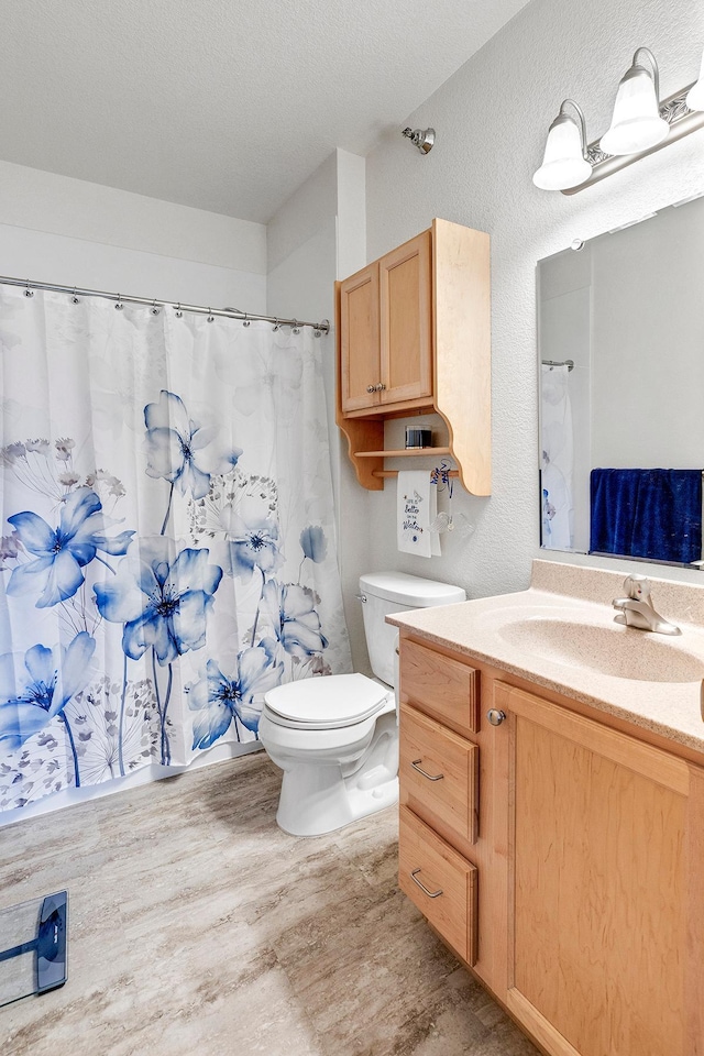 full bath featuring wood finished floors, toilet, vanity, a shower with shower curtain, and a textured wall
