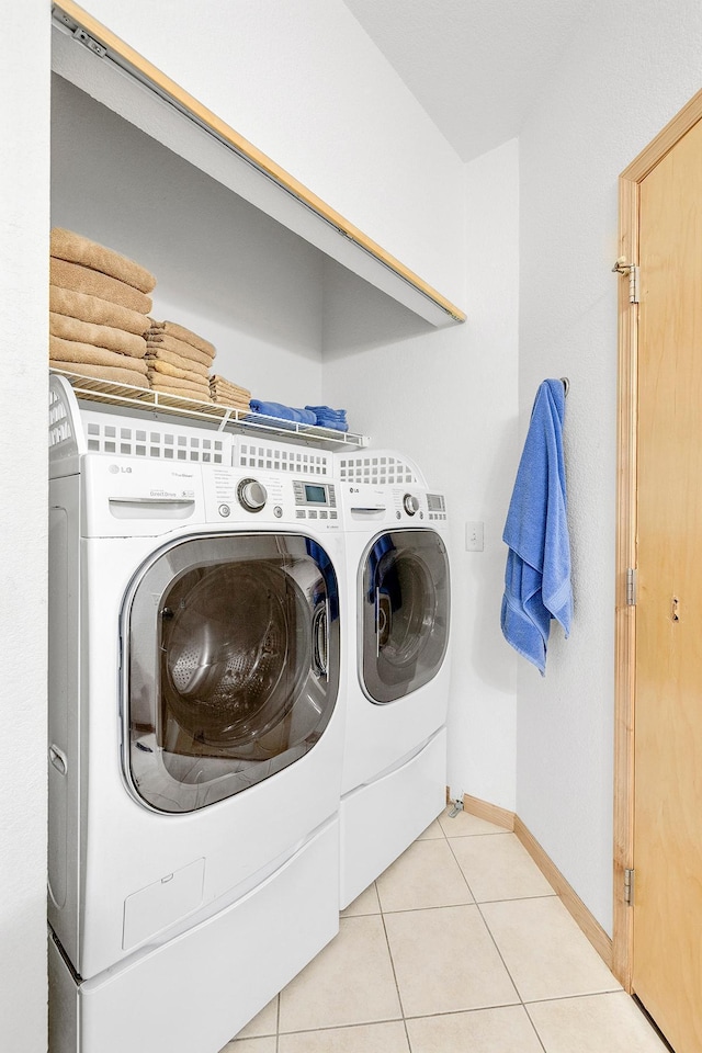 washroom with separate washer and dryer, baseboards, and light tile patterned floors