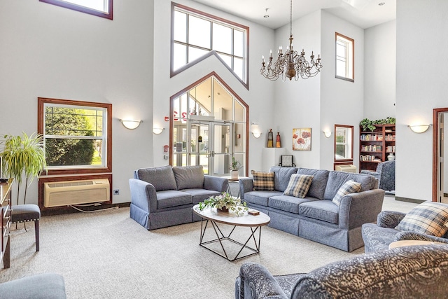 living room featuring a towering ceiling, a wall unit AC, a chandelier, and carpet floors