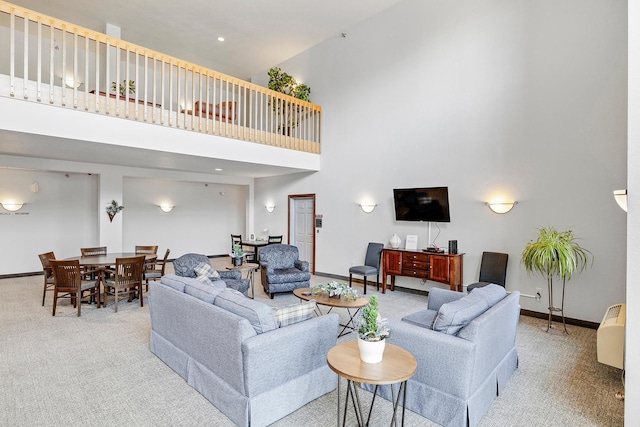 living room with carpet flooring, a towering ceiling, and baseboards