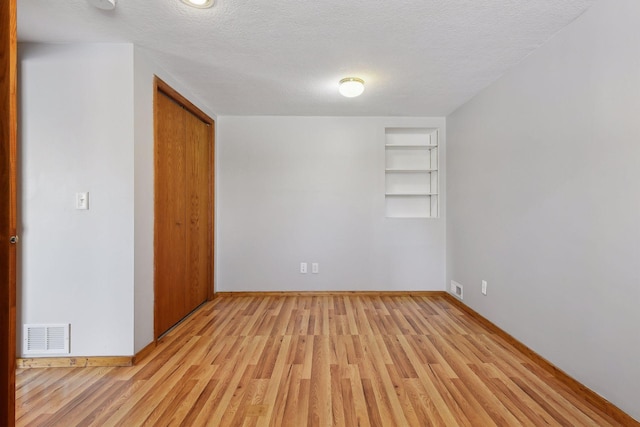 unfurnished bedroom featuring light wood-type flooring, baseboards, a textured ceiling, and a closet