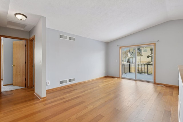 unfurnished room featuring vaulted ceiling, light wood-style floors, and baseboards