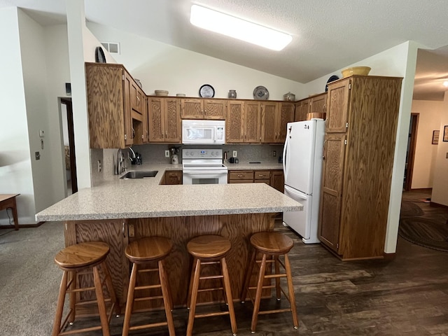 kitchen with white appliances, a sink, vaulted ceiling, a peninsula, and light countertops