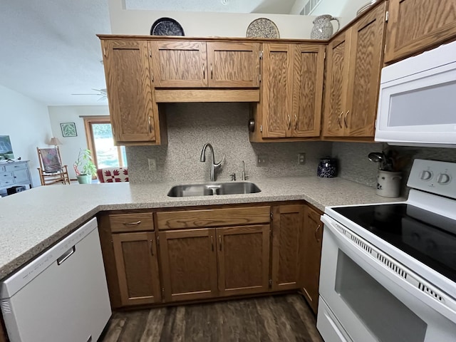 kitchen with white appliances, a sink, light countertops, dark wood-style flooring, and a peninsula