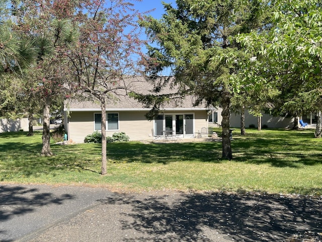 view of front of home featuring a patio, a front lawn, and a shingled roof