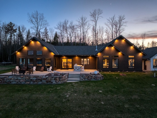rear view of property featuring a fire pit, a patio, and a lawn