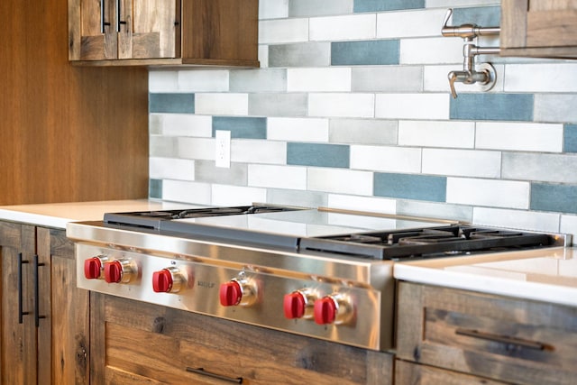 kitchen featuring stainless steel gas stovetop, backsplash, light countertops, and brown cabinets