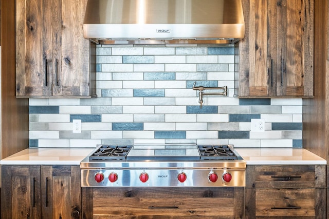 kitchen featuring dark brown cabinetry, exhaust hood, light countertops, stainless steel gas stovetop, and tasteful backsplash