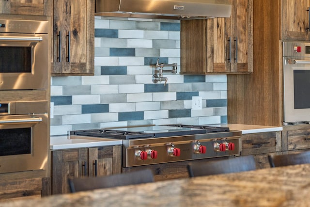 kitchen with under cabinet range hood, stainless steel appliances, and backsplash