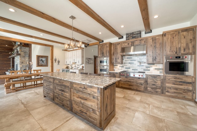 kitchen with pendant lighting, beamed ceiling, under cabinet range hood, tasteful backsplash, and stainless steel gas cooktop