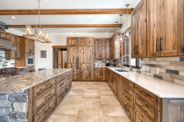 kitchen with a sink, ventilation hood, decorative backsplash, brown cabinets, and oven