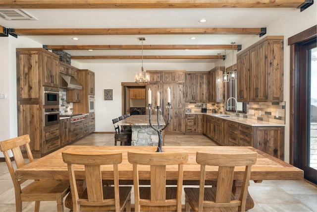 kitchen with a sink, tasteful backsplash, visible vents, under cabinet range hood, and light countertops