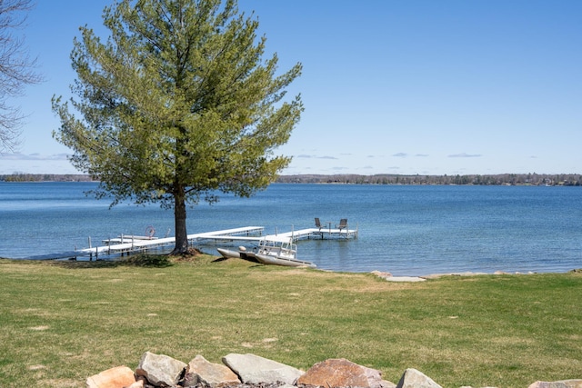 view of dock with a lawn and a water view