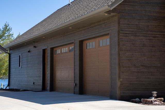 exterior space with a shingled roof and a garage
