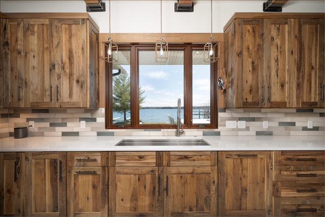 kitchen with brown cabinetry, light countertops, tasteful backsplash, and a sink