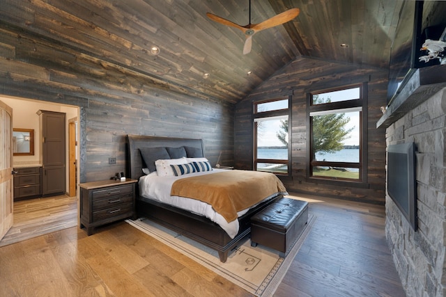 bedroom with light wood-style floors, wood walls, wooden ceiling, and vaulted ceiling