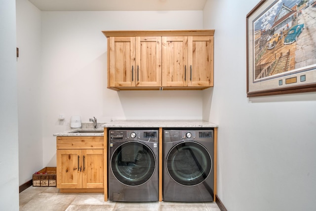 washroom featuring a sink, separate washer and dryer, cabinet space, and baseboards