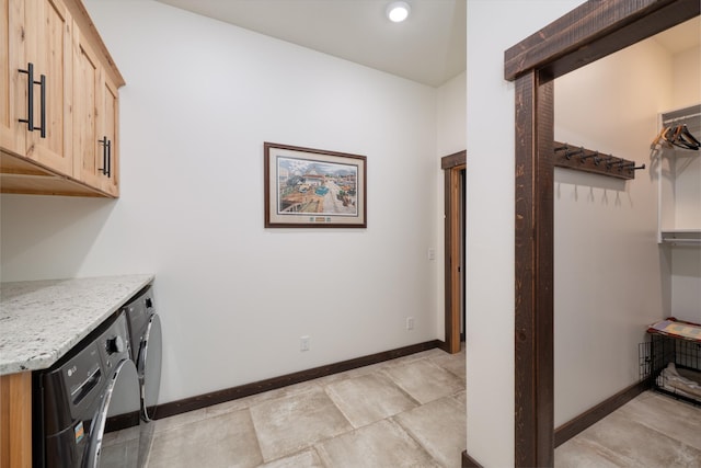 clothes washing area with baseboards, washer and dryer, and cabinet space