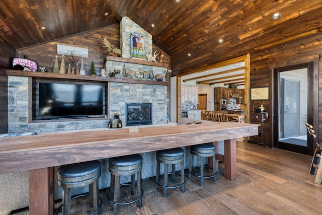interior space featuring vaulted ceiling, a stone fireplace, wood ceiling, wood walls, and wood finished floors