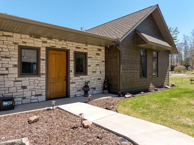 view of front of home with covered porch, stone siding, roof with shingles, and a front lawn