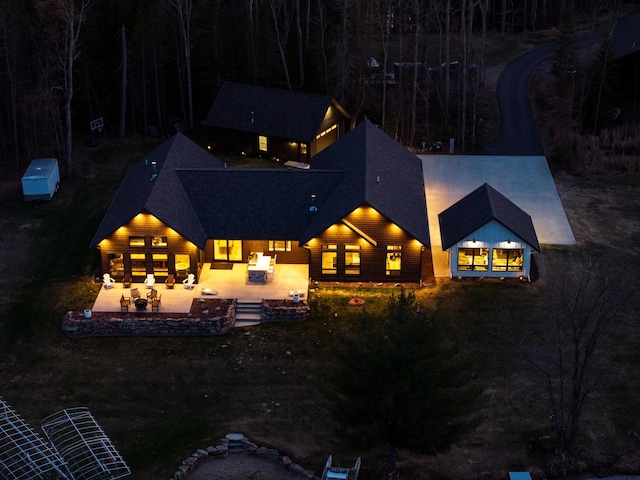 exterior space with a fire pit, a shingled roof, and a patio