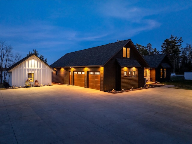 view of front of property with board and batten siding, roof with shingles, a garage, and driveway